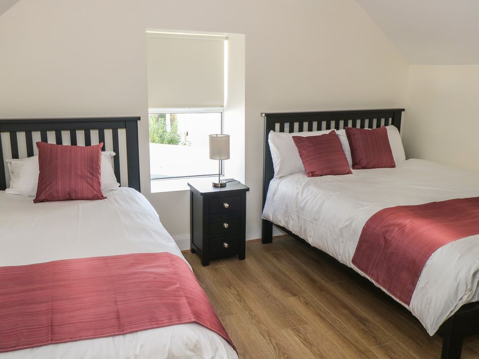 A bedroom with two beds and a nightstand at Greenfield House in Aughavas
