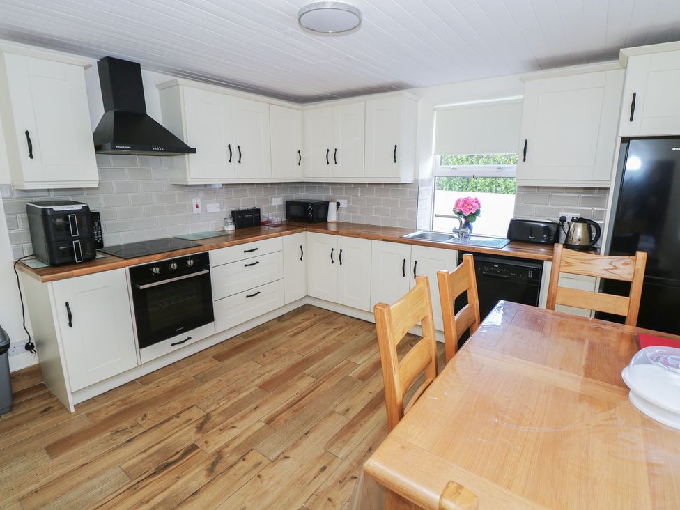 A kitchen with cabinets, an oven, and a dining table at Greenfield House, Aughavas, County Leitrim