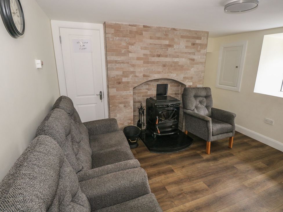 A living room with a sofa, an armchair, and a fireplace at Greenfield House, Aughavas, County Leitrim