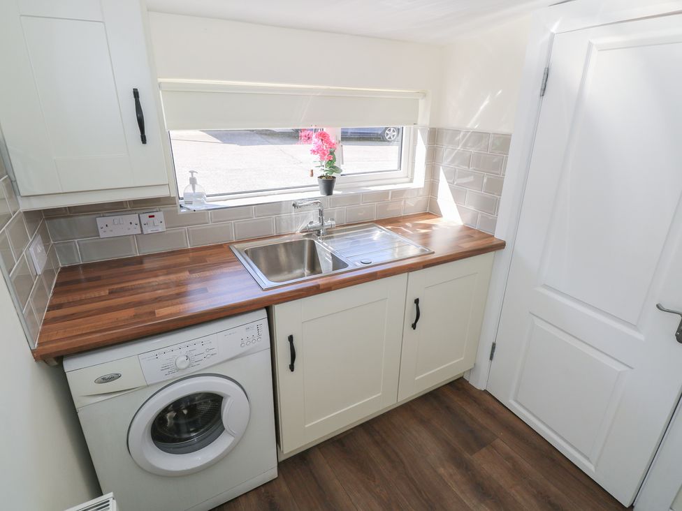 A laundry room with a washing machine and sink at Greenfield House Aughavas, County Leitrim