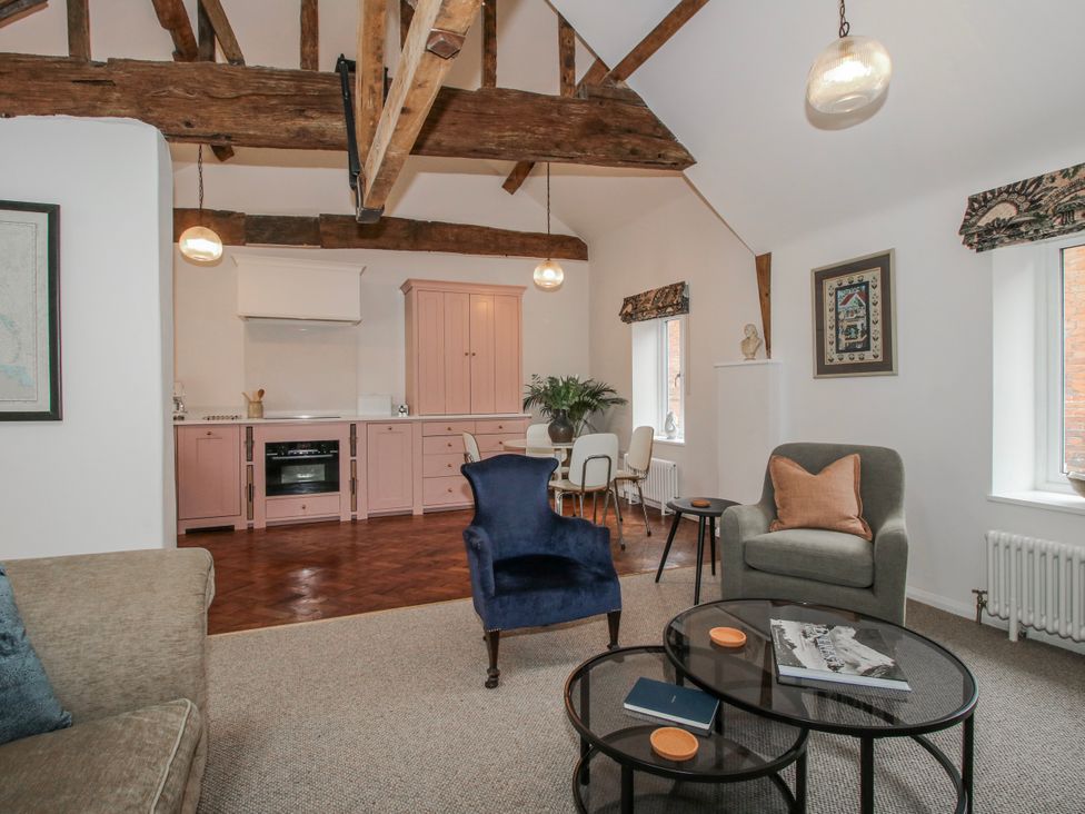 A living room with a sofa, chairs and a kitchen unit at The Old China Shop in Ludlow