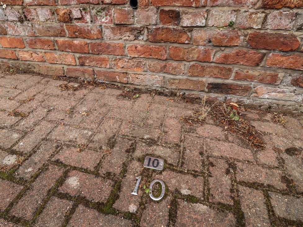 A number 10 plaque on paving stones next to a brick wall at 10 Church Walks in Christleton