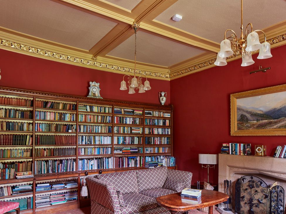 A library with a bookshelf and sofa at Uphill Manor in Uphill near Weston-Super-Mare