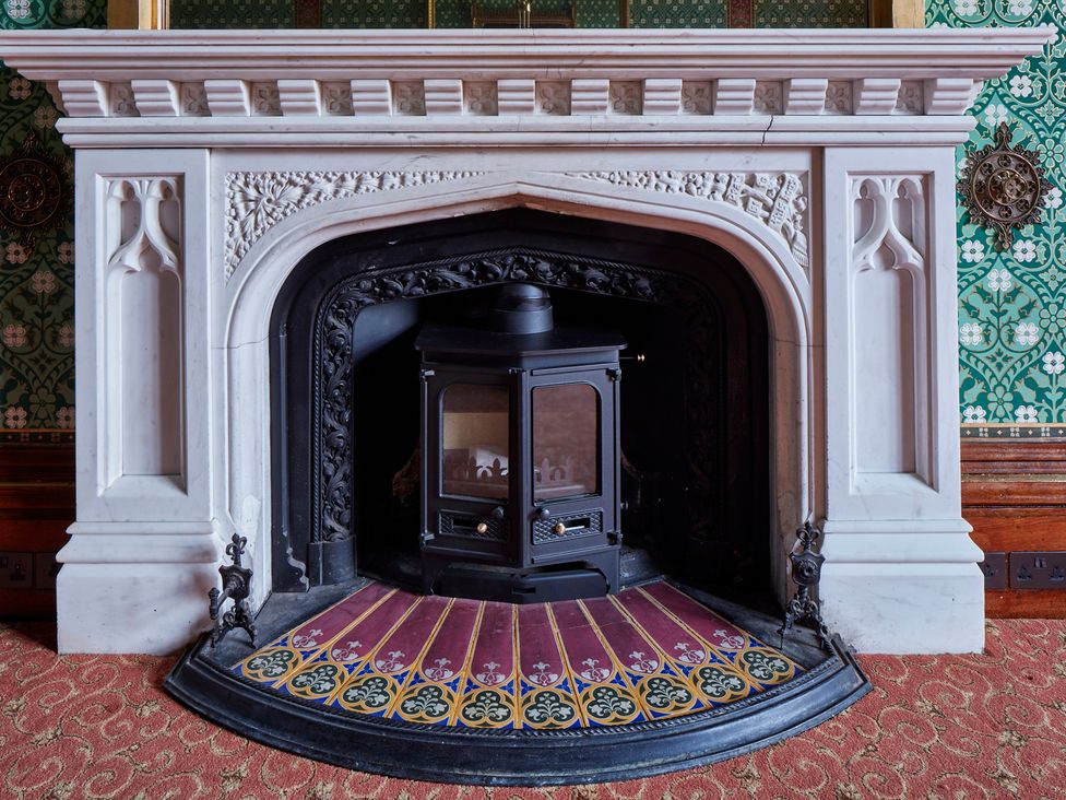 A fireplace with a wood stove in a living room at Uphill Manor Uphill near Weston-Super-Mare