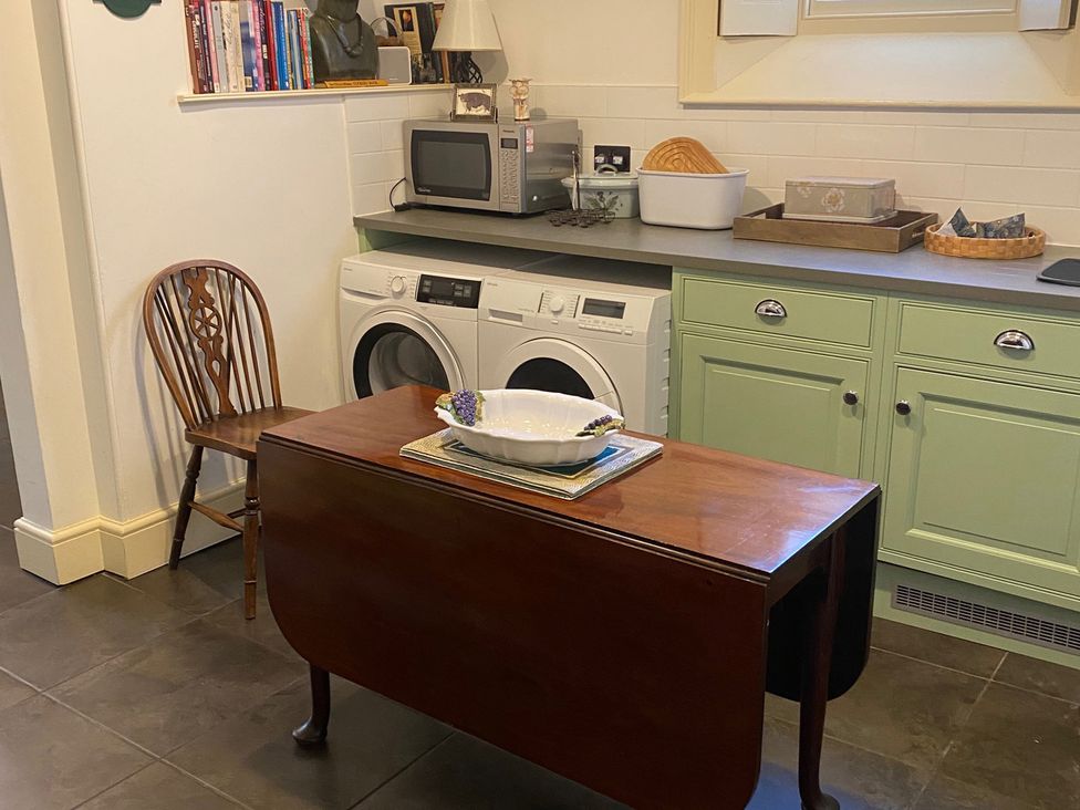 A utility room with a washing machine and a microwave at Uphill Manor Uphill near Weston-Super-Mare