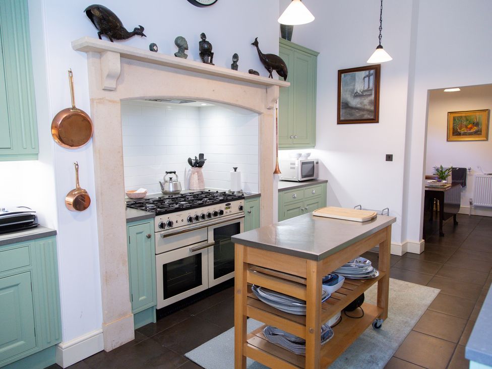 A kitchen with a stove, countertop and kitchen island at Uphill Manor Uphill near Weston-Super-Mare