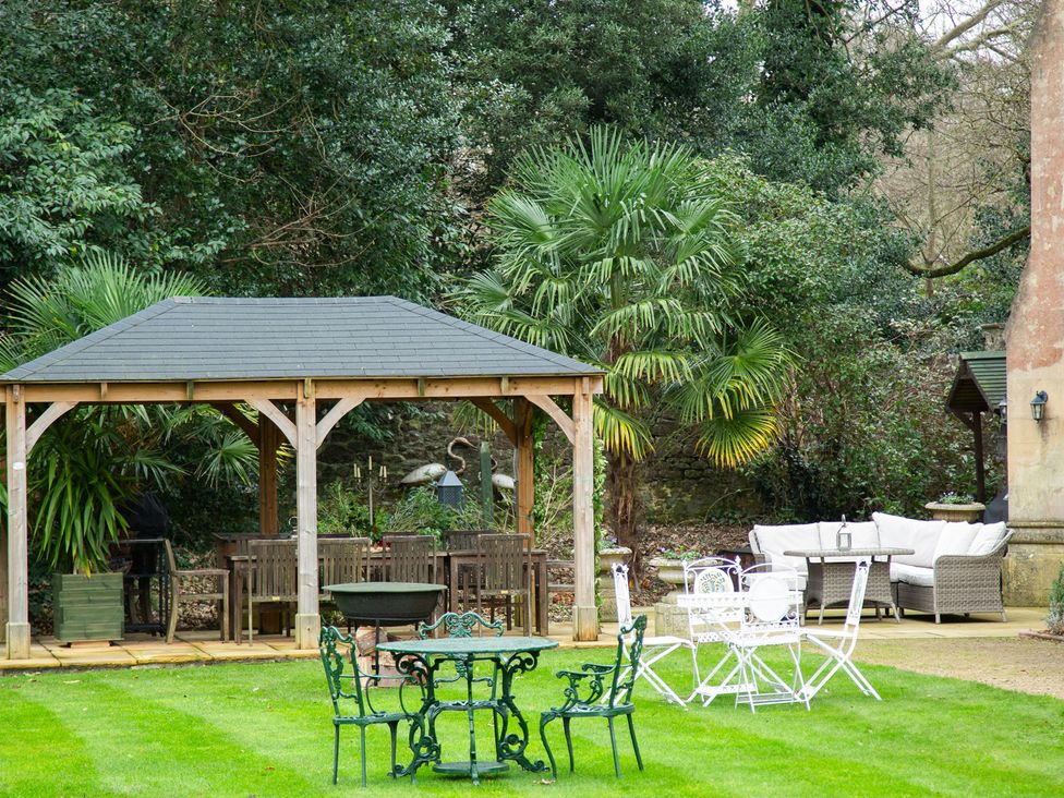 A gazebo with seating and palm trees at Uphill Manor, Uphill near Weston-Super-Mare