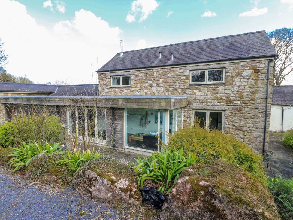 A stone house with windows and plants in front at Too Hoots Lligwy