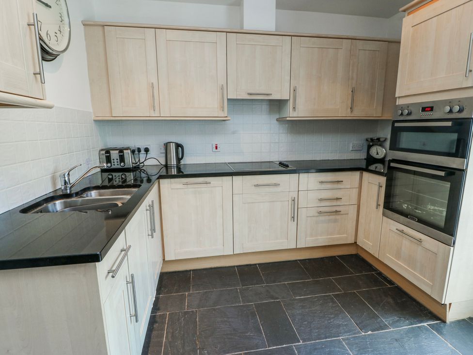 A kitchen with cabinets countertop and appliances at Too Hoots in Lligwy