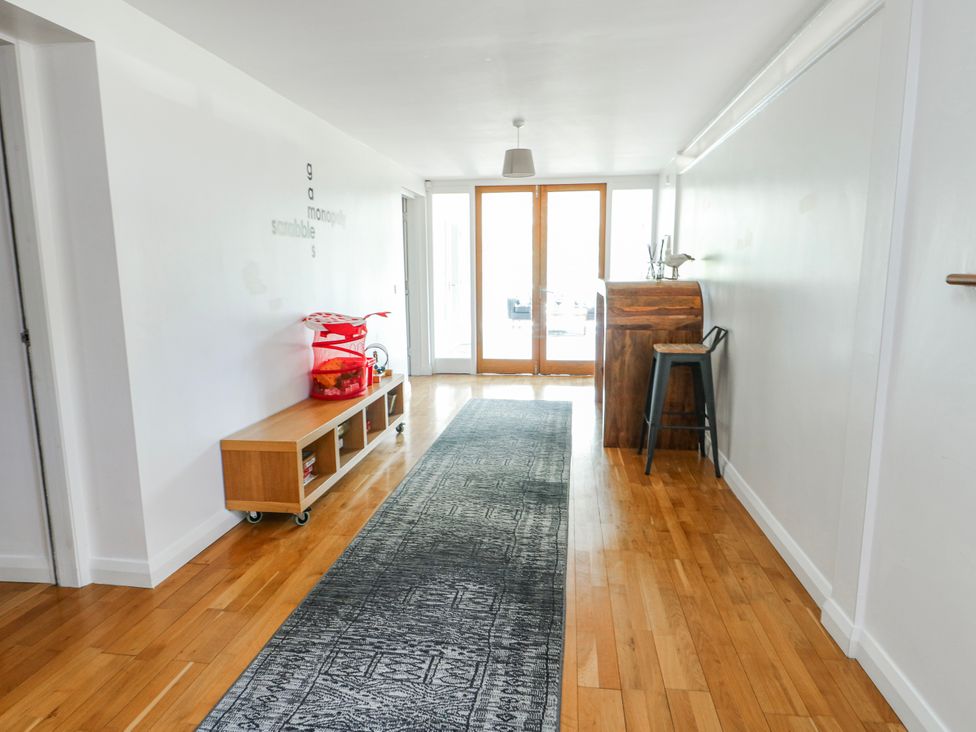 A hallway with a wooden bench and bar stool at Too Hoots in Lligwy