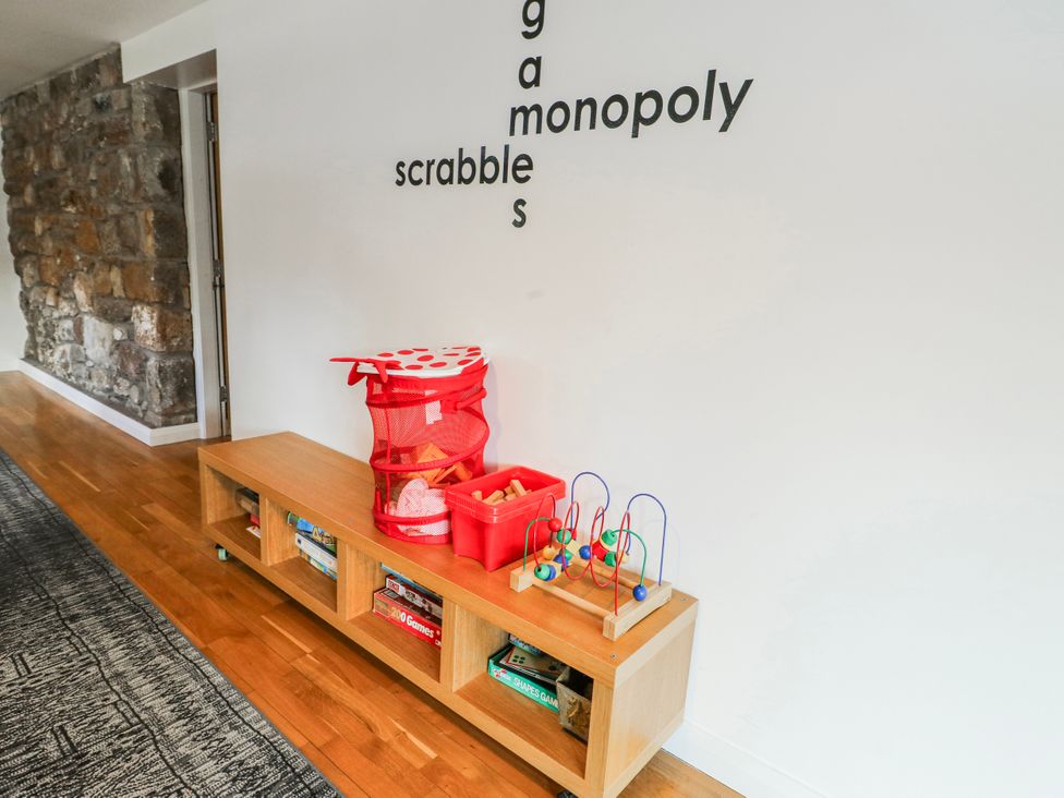 A playroom with a storage unit and games at Too Hoots in Lligwy