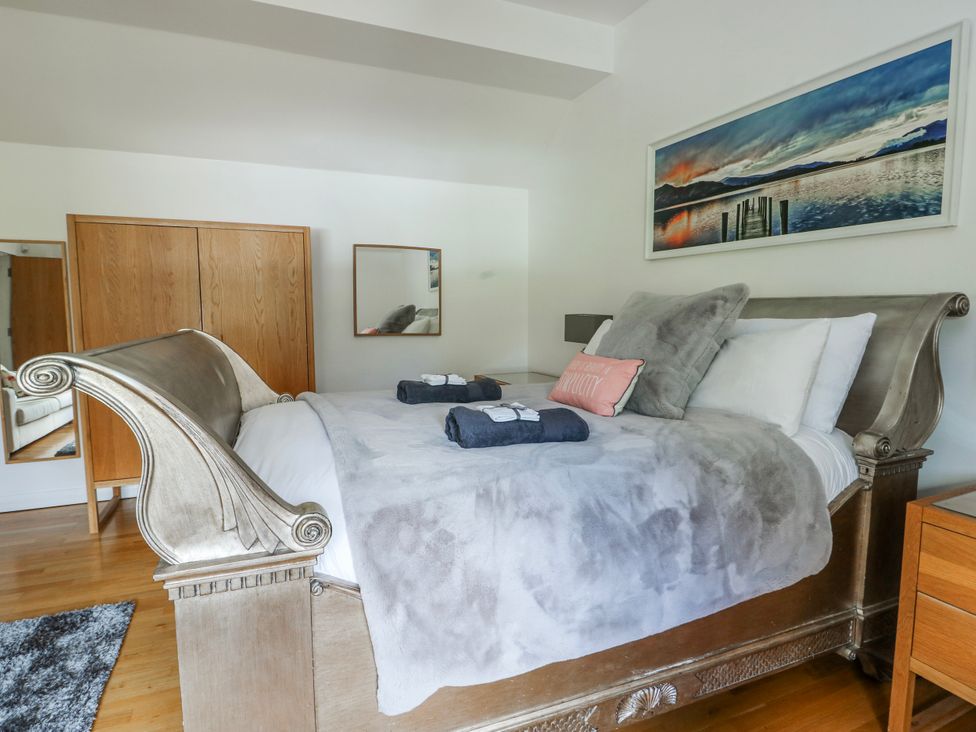 A bedroom with a bed and wardrobe at Too Hoots in Lligwy