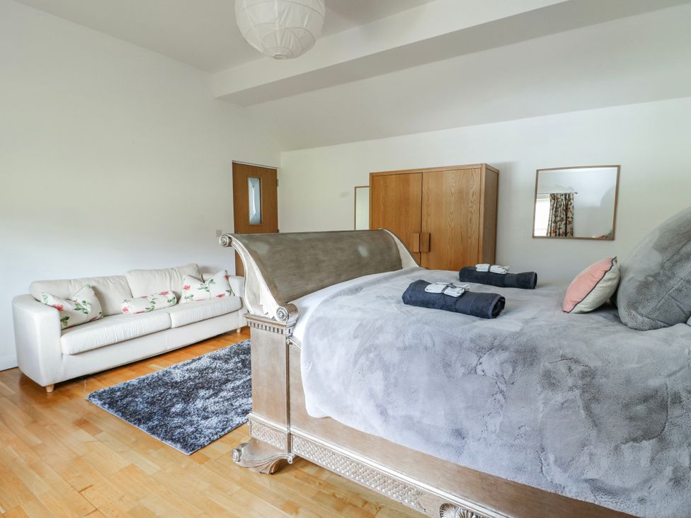 A bedroom with a bed and a sofa at Too Hoots in Lligwy