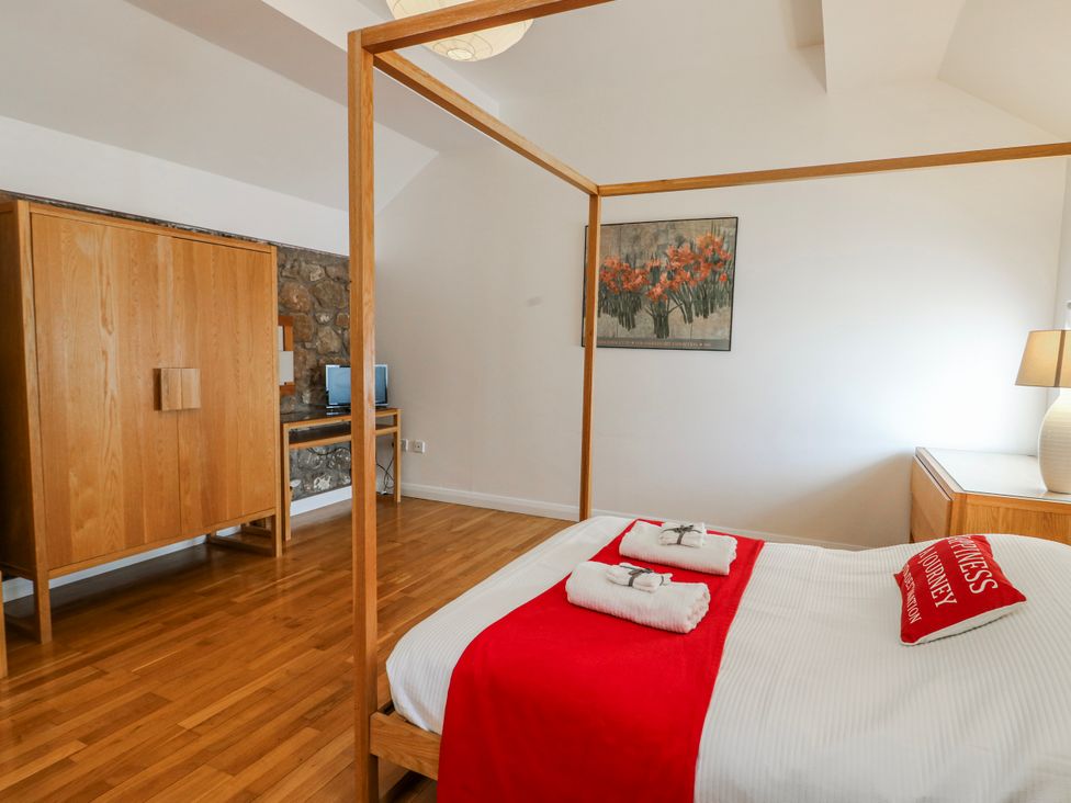 A bedroom with a bed and wardrobe at Too Hoots in Lligwy