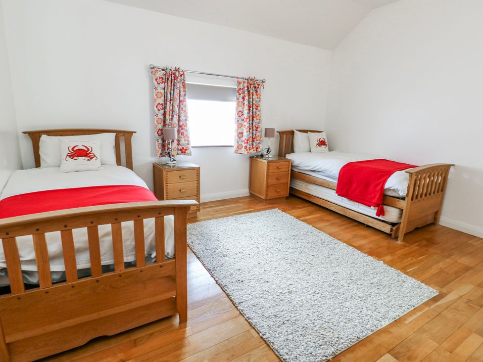 A bedroom with two beds and a nightstand at Too Hoots in Lligwy