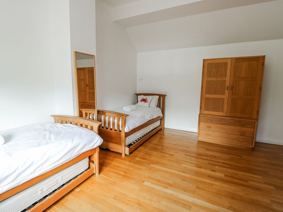 A bedroom with two beds and a wardrobe at Too Hoots in Lligwy