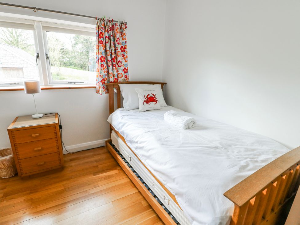 A bedroom with a single bed and nightstand at Too Hoots in Lligwy