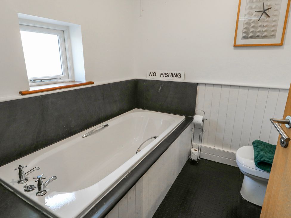 A bathroom with a bath tub and toilet at Too Hoots in Lligwy