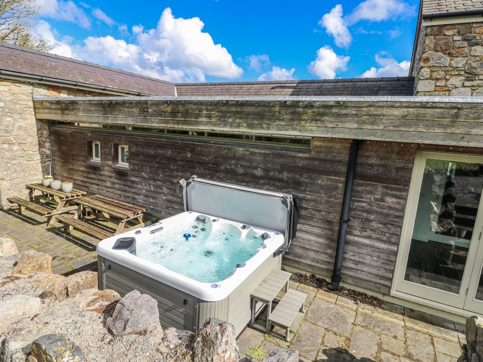 A hot tub on a patio area at Too Hoots in Lligwy