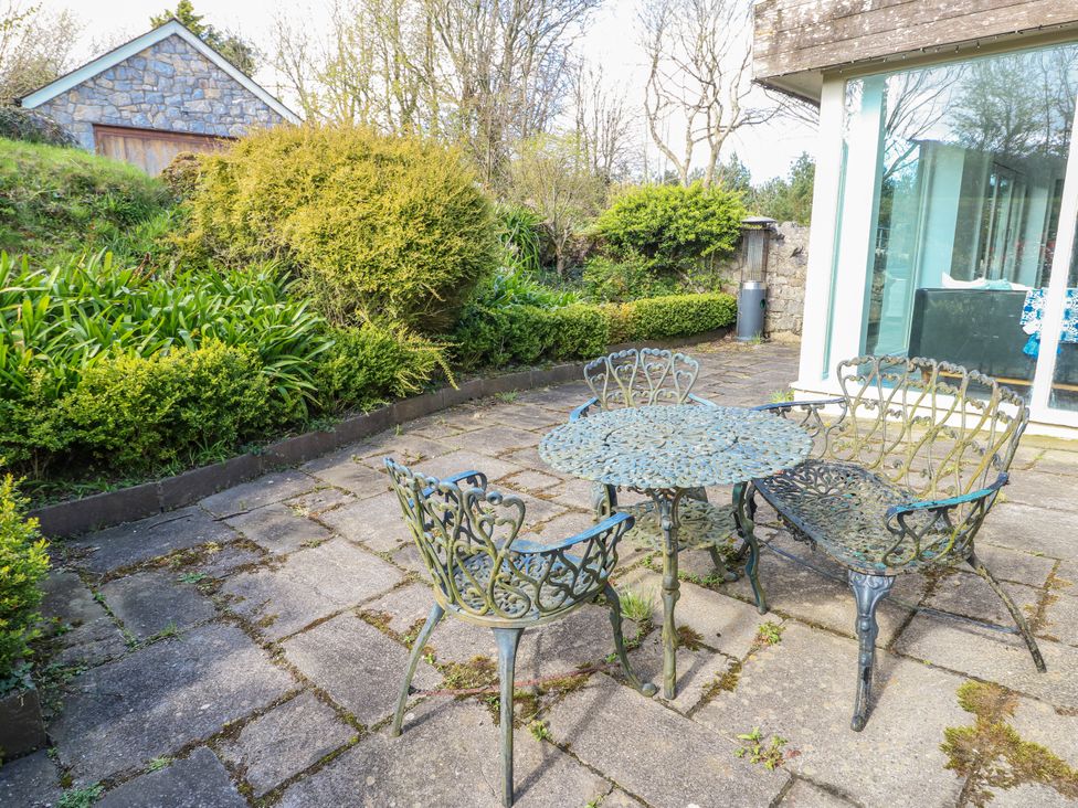 A garden with a stone patio and metal furniture at Too Hoots in Lligwy