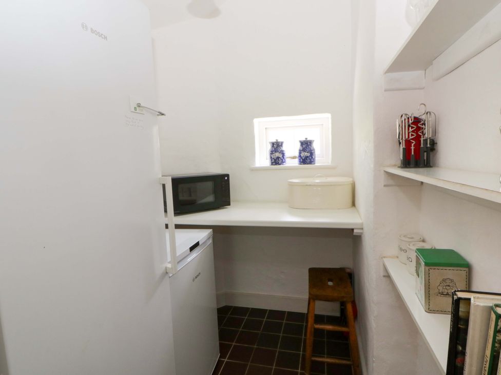 A kitchen with a refrigerator, countertop, and microwave at Cynefin in Newport, Pembrokeshire