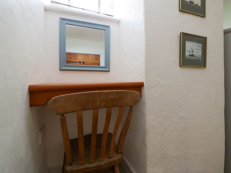A nook with a chair and table under a mirror at Cynefin Newport, Pembrokeshire