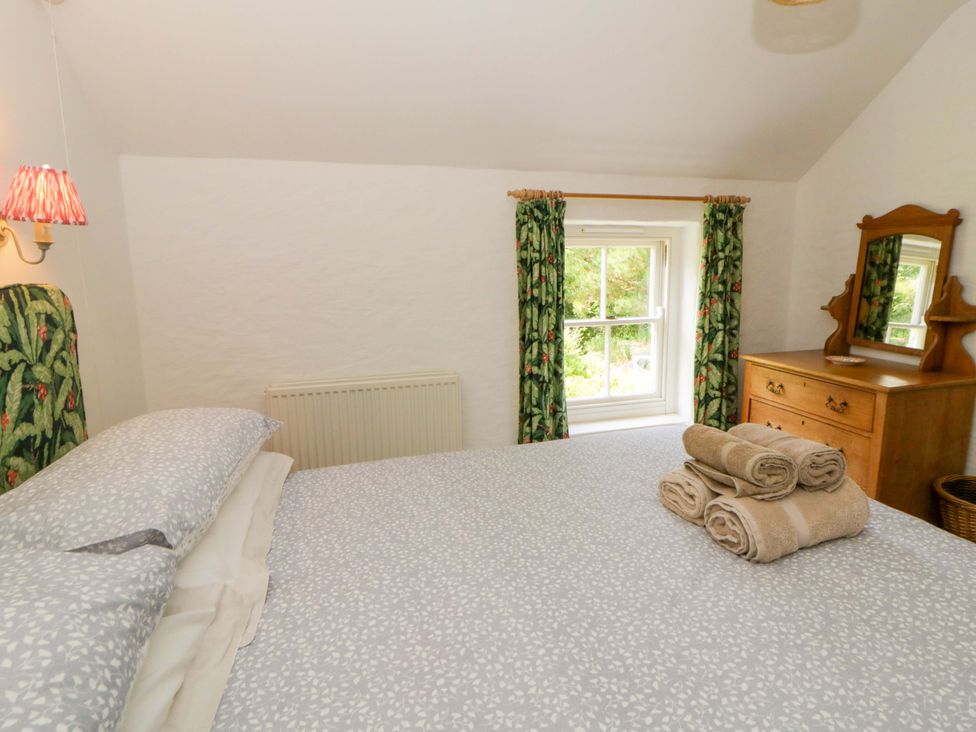A bedroom with a bed and dresser at Cynefin in Newport, Pembrokeshire