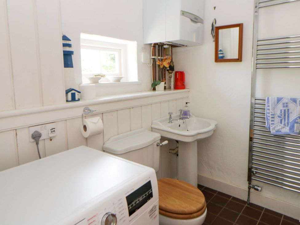 A bathroom with a washing machine and a sink at Cynefin in Newport, Pembrokeshire