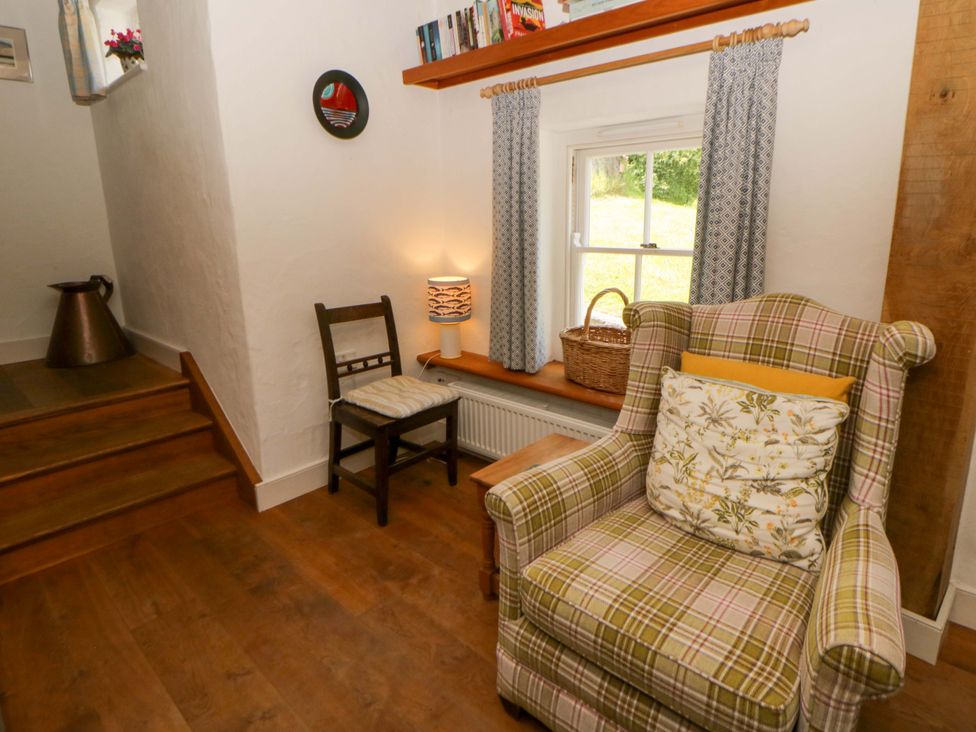 A living room with an armchair and a window at Cynefin in Newport, Pembrokeshire