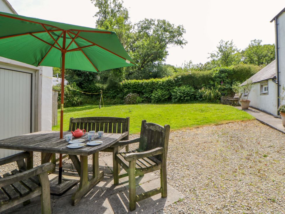 A garden with a table and chairs under an umbrella at Cynefin in Newport, Pembrokeshire