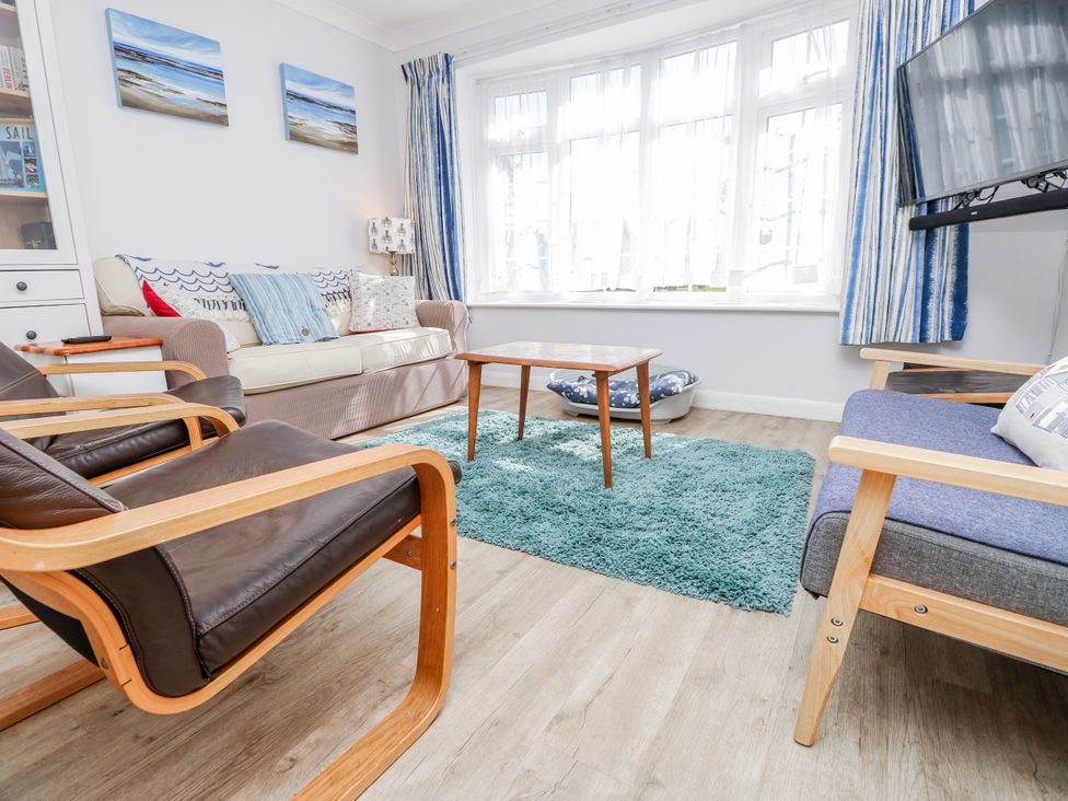 A living room with a sofa, armchairs, coffee table, and television at 2 Trelawny Way, Bembridge