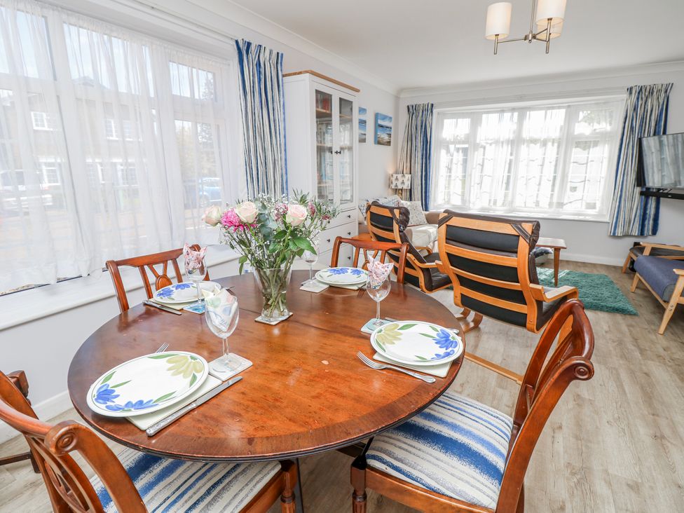 A dining room with a round table and flowers at 2 Trelawny Way in Bembridge