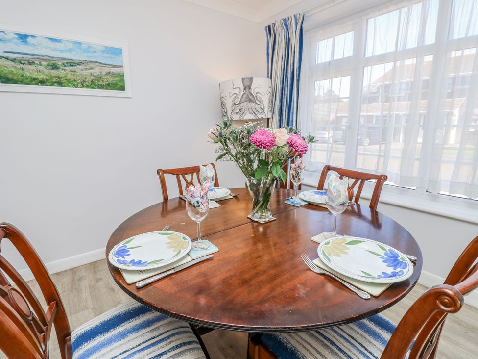 A dining room with a round table set for a meal at 2 Trelawny Way Bembridge
