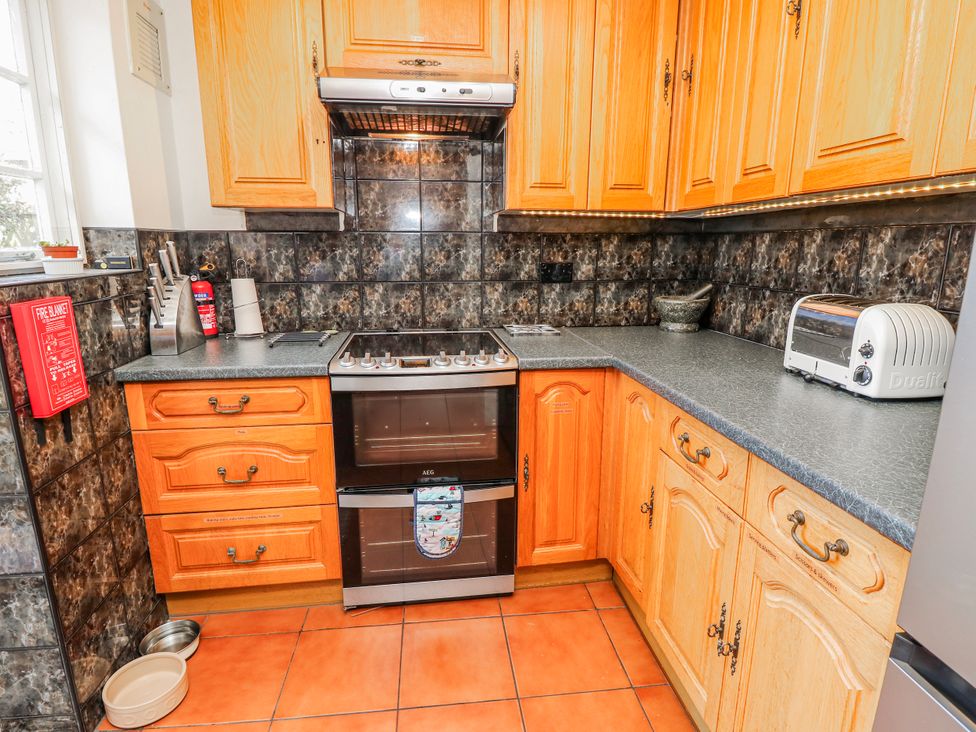 A kitchen with a cooker, toaster, and cabinets at 2 Trelawny Way in Bembridge