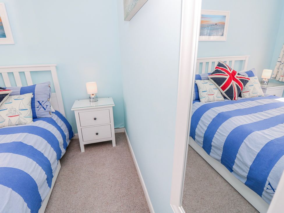 A bedroom with a bed and bedside table at 2 Trelawny Way in Bembridge
