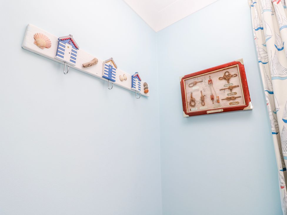 A bathroom with wall hooks and framed display at 2 Trelawny Way Bembridge