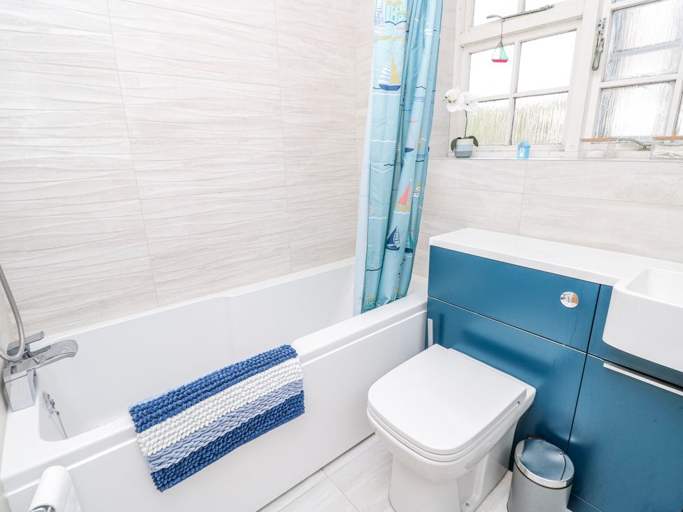 A bathroom with a bathtub and shower curtain at 2 Trelawny Way Bembridge