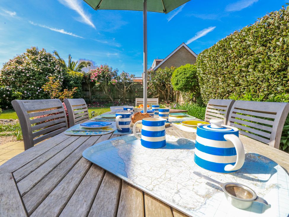 A garden table set for tea with a striped teapot and cup at 2 Trelawny Way Bembridge