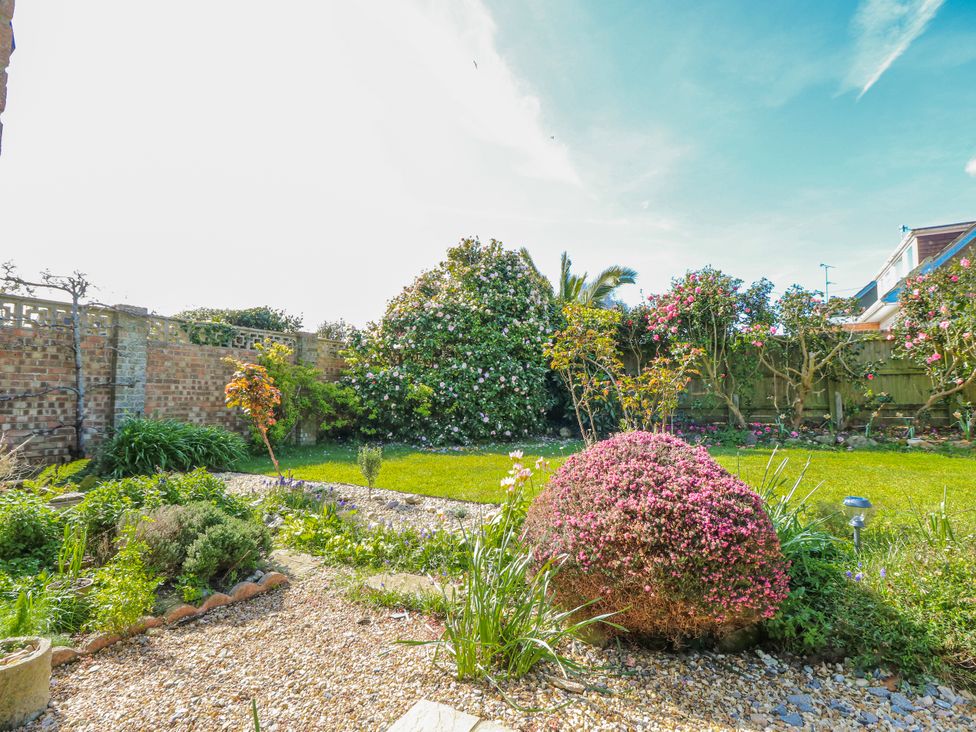 A garden with flowering shrubs and a grassy area at 2 Trelawny Way in Bembridge