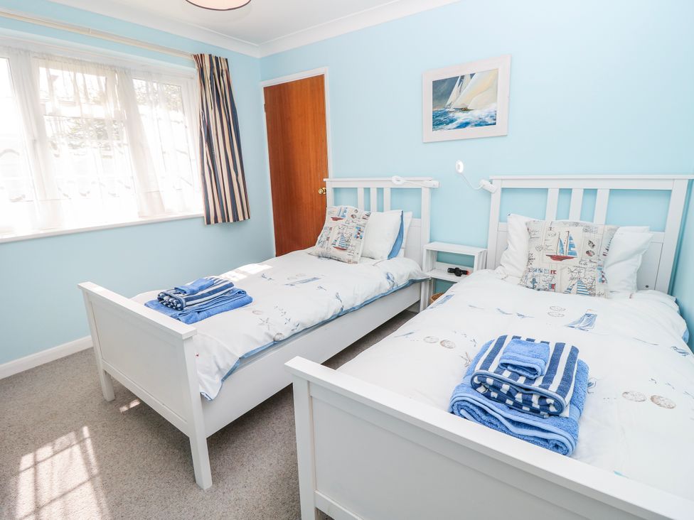 A bedroom with two beds and a window at 2 Trelawny Way in Bembridge