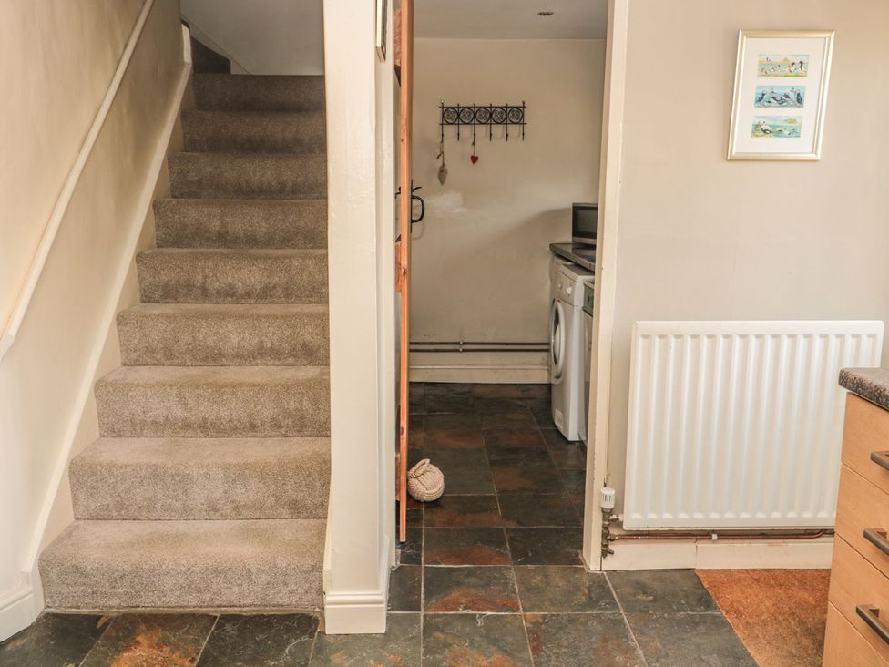 A kitchen with stairs and washing machine at Shepherds Nook in Chathill