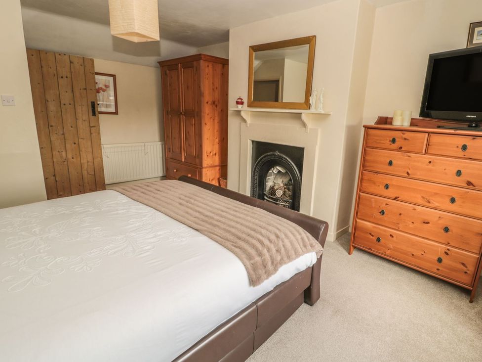 A bedroom with a bed, dresser, television, and fireplace at Shepherds Nook in Chathill