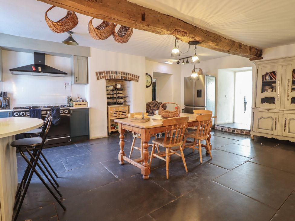 A kitchen with a dining table and stove at Plas Dolguog in Machynlleth