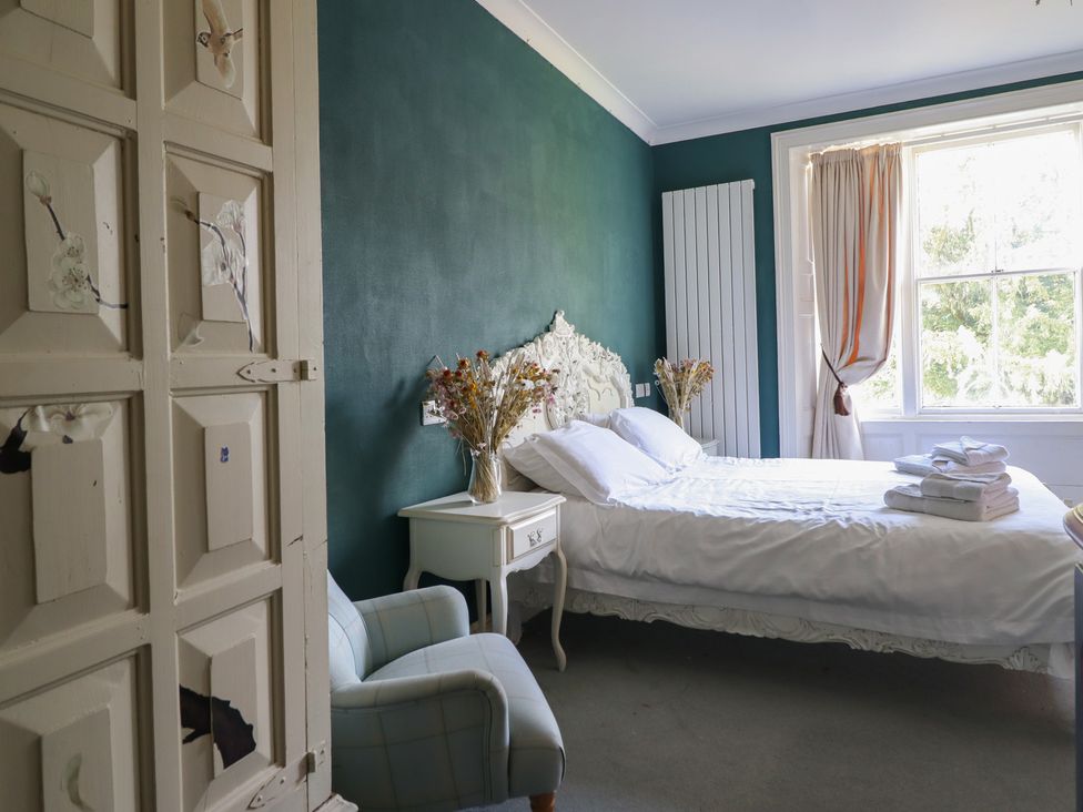 A bedroom with a bed and armchair at Plas Dolguog in Machynlleth
