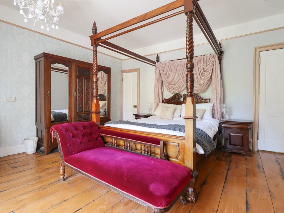 A bedroom with a four-poster bed and a wardrobe at Plas Dolguog in Machynlleth