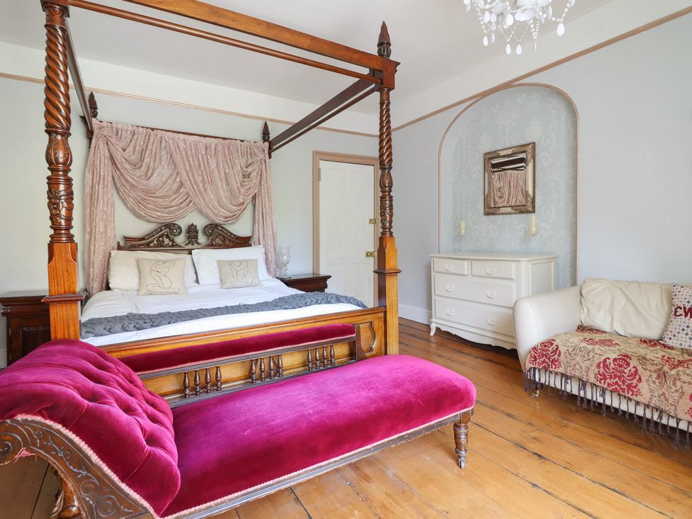 A bedroom with a four-poster bed and a chest of drawers at Plas Dolguog in Machynlleth