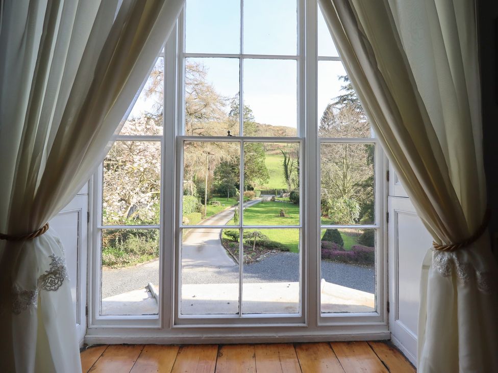 A view of a garden and driveway through a window at Plas Dolguog in Machynlleth