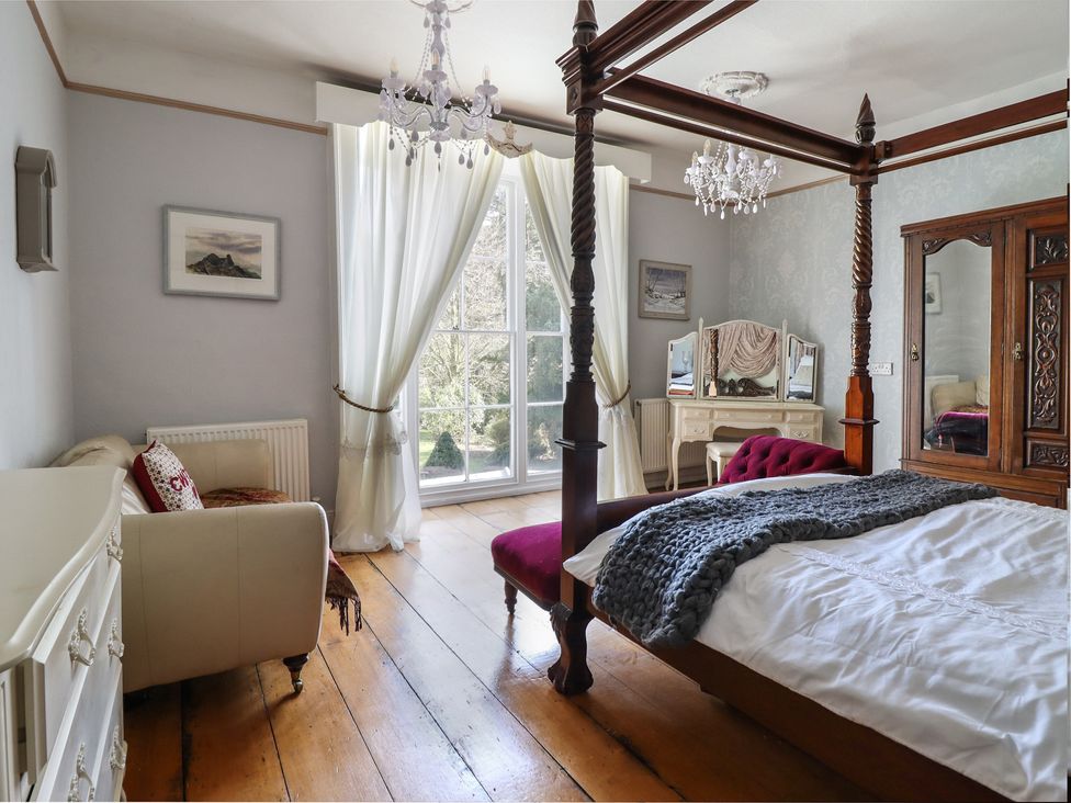 A bedroom with a four-poster bed and a dresser at Plas Dolguog in Machynlleth