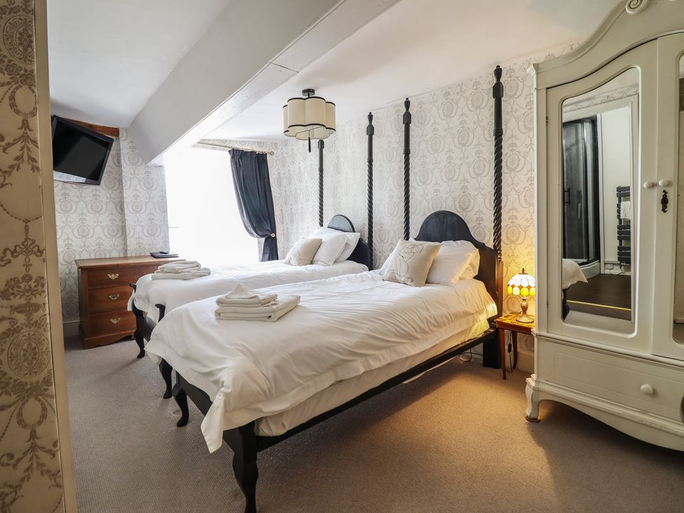 A bedroom with two beds and a wardrobe at Plas Dolguog in Machynlleth