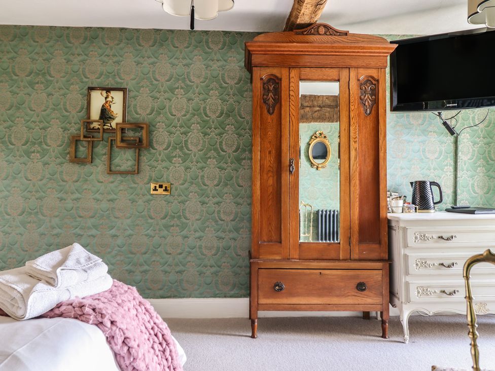 A bedroom with a wooden wardrobe and a television at Plas Dolguog in Machynlleth
